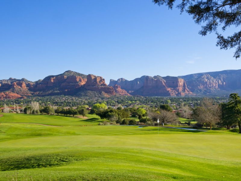 A beautiful golf course in the Village of Oak Tree, near Sedona. The red rocks in the background under a clear blue sky are illuminated by the early morning sun.